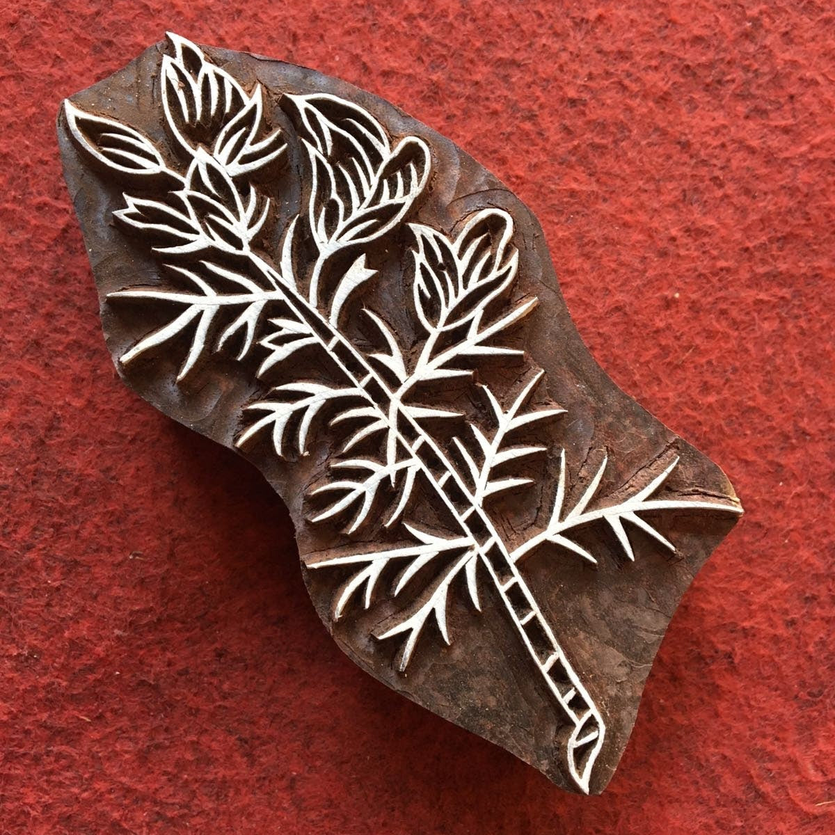 Wooden stamp with leaf design on a red background